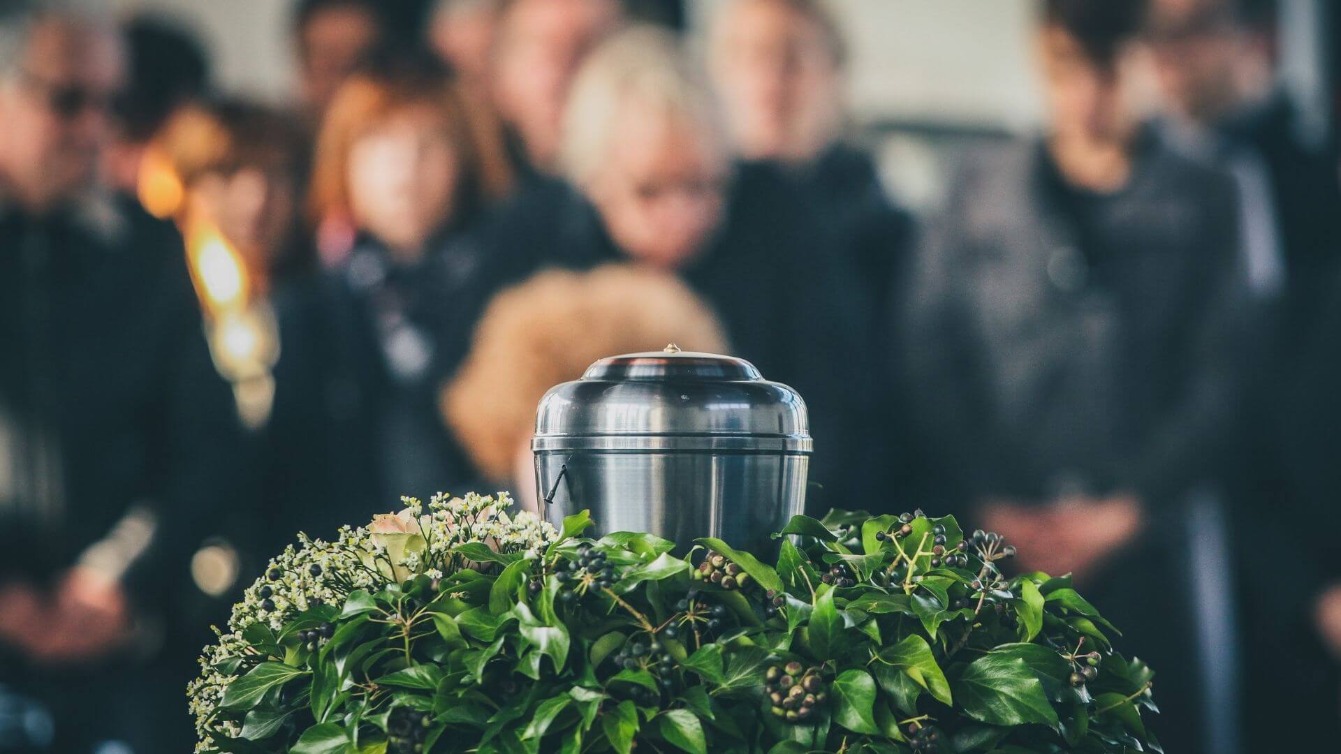 教会の葬儀参列者と花に囲まれた骨壷