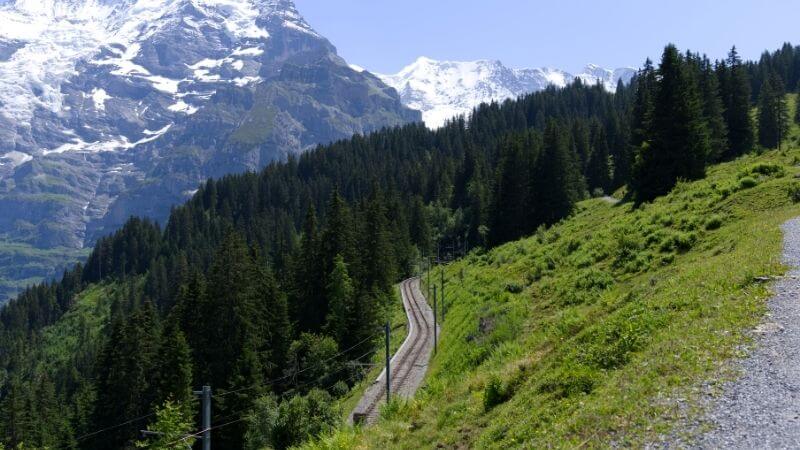 ミューレンへと向かう線路とアルプスの森と山並み